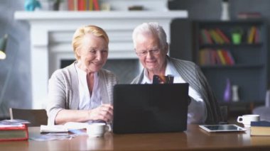 Yaşlı çift rahat oturma odasında internette aile ile iletişim içinde eğleniyor