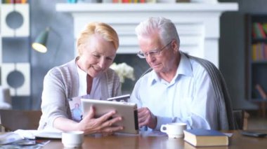 Yaşlı çift rahat oturma odasında internette aile ile iletişim içinde eğleniyor