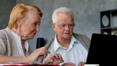 Üst düzey çift websurfing dizüstü bilgisayar ile Internet üzerinde. Mutlu yaşlı adam ve bilgisayar kullanan kadın