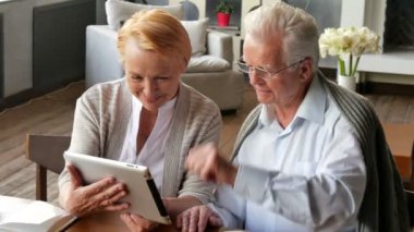 Üst düzey çift websurfing tablet ile internet üzerinde. Mutlu yaşlı adam ve tablet bilgisayar kullanan kadın