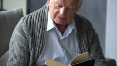 yaşlı beyaz adam modern bir dairede bir kitap okuma