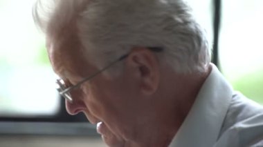 elderly man sits in a chair and speak at phone in a modern apartment