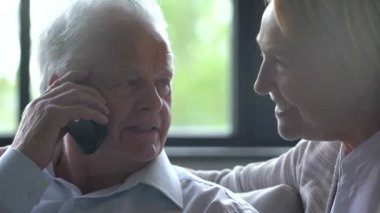 happy elderly couple talking on the phone with grandchildren and holding hands
