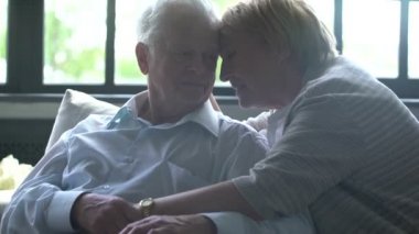 sevgi dolu ve mutlu yaşlı çift modern bir daire. Onlar konuşmak, gülümse, sarılmak ve birbirlerine öpücük