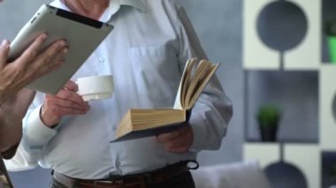 Mutlu çift ayakta birbirimizi karşısında tablet ve kitap ile güzel emekli. Onlar gülümseme.