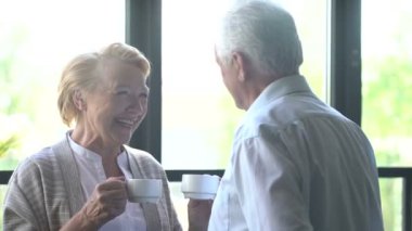 sevgi dolu ve mutlu yaşlı çift modern bir daire. konuşma, çay ve gülmek iç