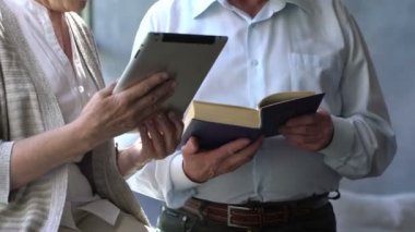 Mutlu çift ayakta birbirimizi karşısında tablet ve kitap ile güzel emekli. Onlar gülümseme.