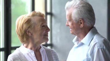 sevgi dolu ve mutlu yaşlı çift modern bir daire. Onlar konuşma ve gülümseme