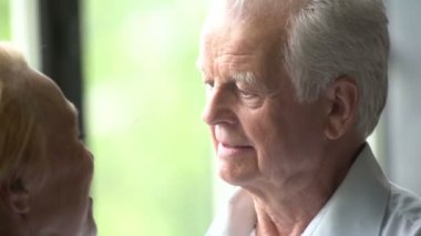 sevgi dolu ve mutlu yaşlı çift modern bir daire. Onlar konuşmak, gülümse, sarılmak ve birbirlerine öpücük