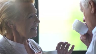 sevgi dolu ve mutlu yaşlı çift modern bir daire. konuşma, çay ve gülmek iç