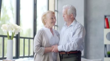 sevgi dolu ve mutlu yaşlı çift modern bir daire. kameraya gülümseyen ve konuşurken, bak