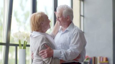 sevgi dolu ve mutlu yaşlı bir sarılma ve modern apartman dairesinde konuşmaya kaç. Kameraya bakarak koca
