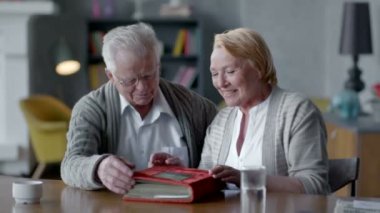 yaşlı mutlu çift birlikte ve nostaljik vakit. Onlar eski fotoğraf albümü arıyorsunuz ve gülümseyen