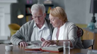 yaşlı mutlu çift birlikte ve nostaljik vakit. Onlar eski fotoğraf albümü arıyorsunuz ve gülümseyen