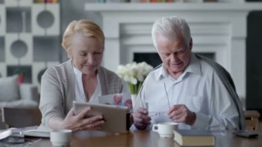 Mutlu güzel emekli çift tablet bilgisayar kullanın. Aile ile iletişim içinde eğleniyor