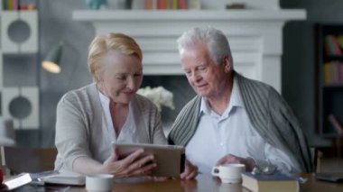 Mutlu güzel emekli çift tablet bilgisayar kullanın. Aile ile iletişim içinde eğleniyor