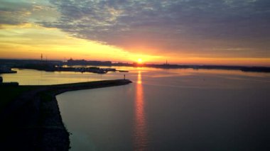 Deniz kıyısında, sakin su, bağlantı noktaları ve şehir üzerinde gündoğumu üzerinde havadan görünümü