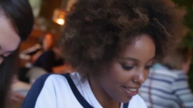 Sohbet ve birlikte kafede çalışan neşeli çeşitli uluslararası öğrenci grubu. Asyalı kız, siyah kız ve zencefil erkekler grafik üzerinde dijital Tablet analiz