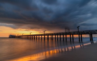 Gün batımında uzun deniz köprüsü Ilık, düşük aydınlık ve karanlık bulutlu gölge.