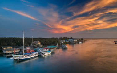 Günbatımının sıcacık ışıklarıyla nehir kıyısında tekneler..