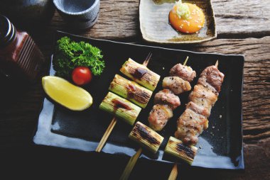 Izakaya barında ızgara edilmiş Japon usulü domuz şişleri, düşük aydınlatma ve koyu gölgeli servis edilir..