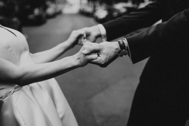 Birbirine aşık çiftlerin el ele tutuşması. El ele tutuşan iki kişi. Sembol, samimi duygular, şefkat ve sevilen birini işaret eder. Romantik bir yürüyüş yapan bir çift. 14 Şubat. Doku. Siyah ve beyaz