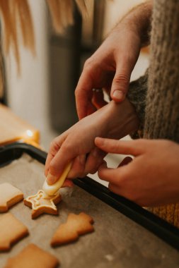 Noel pastası. Noel kurabiyesi pişiriyorum. Yeni pişmiş kurabiyeleri kremayla süsleyerek, yakın plan. Kutlama yemekleri, aile yemekleri, Noel ve Yeni Yıl gelenekleri.