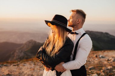 Gün batımında dağın tepesinde duran güzel bir çift.