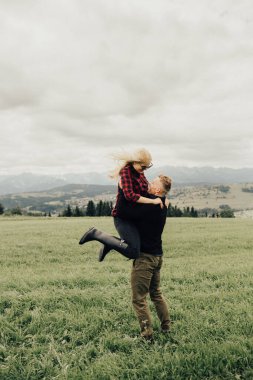 Dağlarda öpüşen ve kucaklaşan bir çift. Panorama görünümü