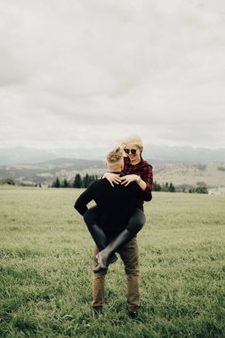 Dağlarda öpüşen ve kucaklaşan bir çift. Panorama görünümü