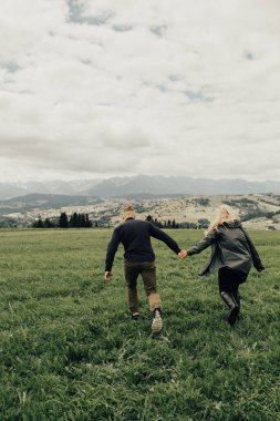 Dağlarda öpüşen ve kucaklaşan bir çift. Panorama görünümü