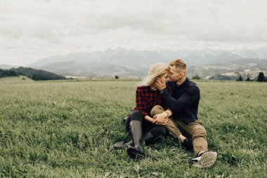 Dağlarda öpüşen ve kucaklaşan bir çift. Panorama görünümü