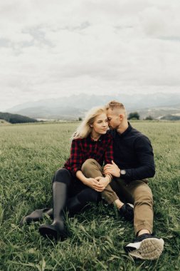 Dağlarda öpüşen ve kucaklaşan bir çift. Panorama görünümü