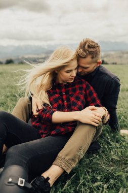 Dağlarda öpüşen ve kucaklaşan bir çift. Panorama görünümü