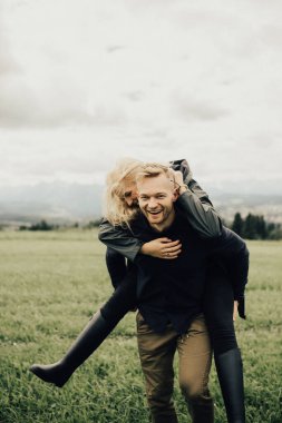 Dağlarda öpüşen ve kucaklaşan bir çift. Panorama görünümü