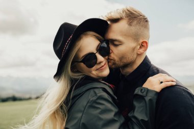 Dağlarda öpüşen ve kucaklaşan bir çift. Panorama görünümü