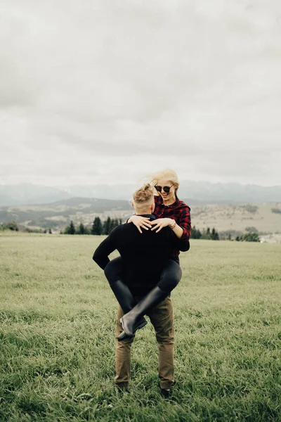 Dağlarda öpüşen ve kucaklaşan bir çift. Panorama görünümü