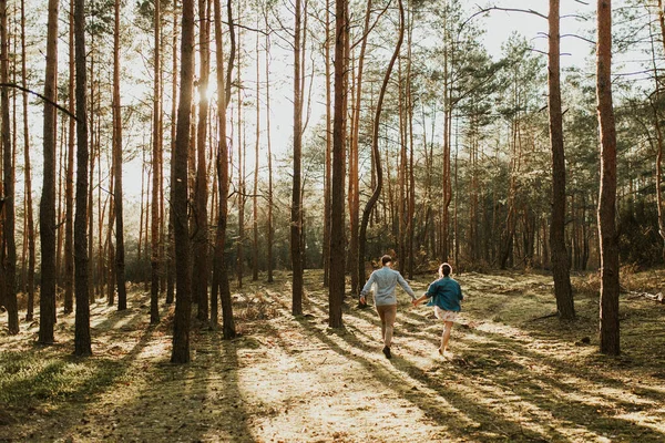 The spirit of travel, freedom and independence. Happy young couple in love running in the field in the sunset light. Messy hair. Freedom and love concept. Close up of holding hands.