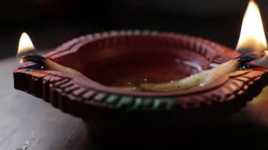 İçinde yağ dolu bir kil diya lambası ve Hinduizm 'deki ateşin kutsallığını gösteren yanan bir pamuk fitili olan bir levha gösteriyor.