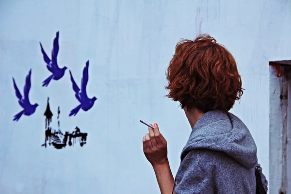 Woman with a cigarette, looking at the wall — Stock Photo, Image