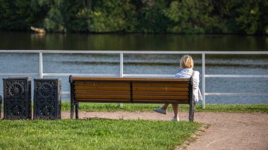 Genç bir kadın bir bankta dinleniyor ve nehre bakıyor..