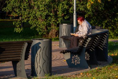 16.09.2020, Moskova, Rusya. Bankta oturan yaşlı bir kadın bahçede kitabı okudu. Parkta dinlenen bir halk..