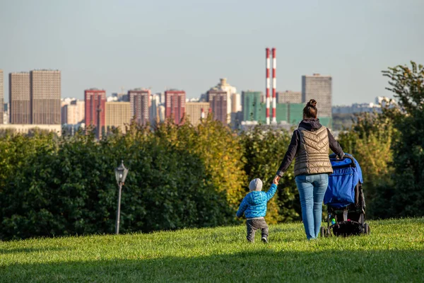 2020年9月16日 俄罗斯莫斯科 一位带着婴儿和婴儿车的年轻女子站在公园的一座山上 望着地平线 在历史性的莫斯科公园散步的人 免版税图库照片
