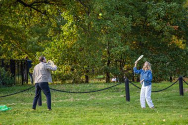 27.09.2020, Moskova, Rusya. Genç bir adam ve kadın sonbahar parkında dışarıda badminton oynuyorlar..