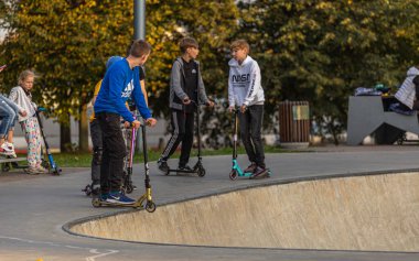 27.09.2020, Moskova, Rusya. Bir grup genç kaykaycı ve scooter 'la parkta geziyor. Açık havada ekstrem sporlar eğitimi.