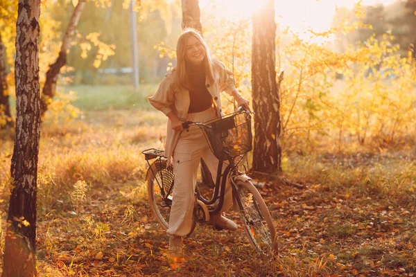 Feliz jovem ativo montando bicicleta vintage no parque de outono ao pôr-do-sol — Fotografia de Stock