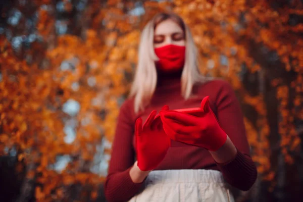 Actieve jonge vrouw met rode handschoenen en gezichtsmasker in het najaarspark met mobiele telefoon — Stockfoto