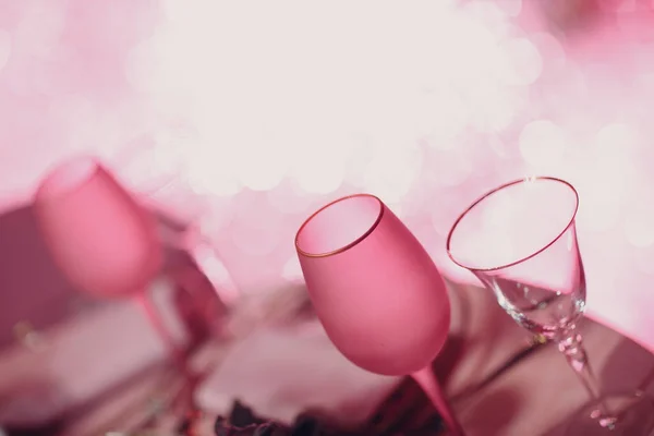 샴페인 두 개가 비어 있고, 탁자 위에 핑크 색 샴페인이 있고, 배경에 반짝이는 보크 라이트가 있다 — 스톡 사진