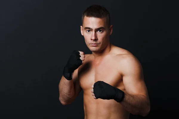 Caballero peleador nudillo desnudo soporte en fondo negro con vendajes de boxeo —  Fotos de Stock