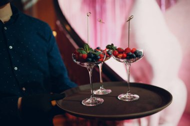 Garson, cam dutlu bir restoranda yemek servisi yapıyor.